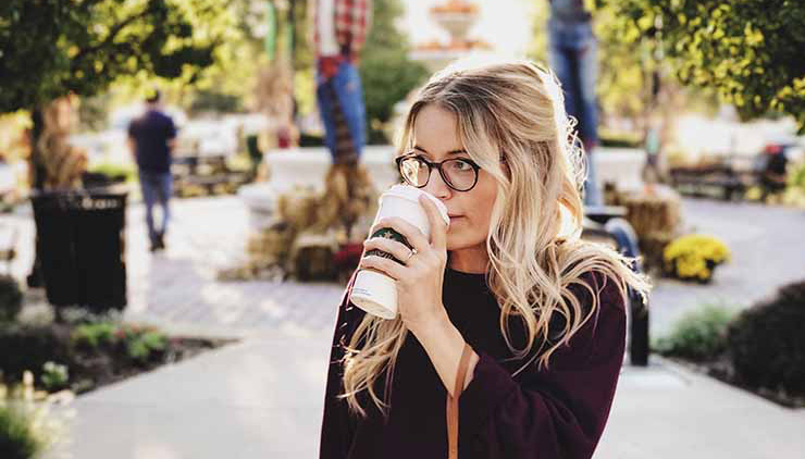 Blonde girl drinking coffee in a beautiful outdoor city