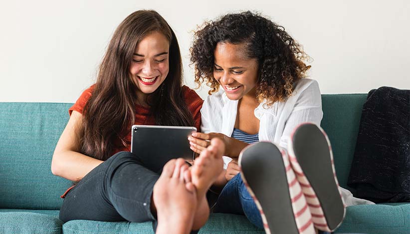 asu roommates sitting on couch using ipad