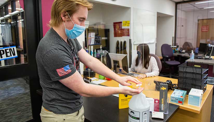 ASU student using hand sanitizer on campus