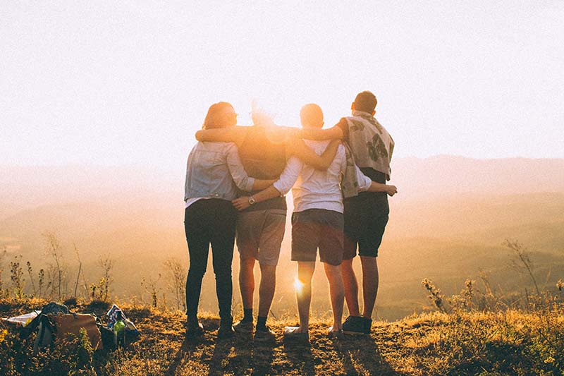 Four friends embracing in the sunset