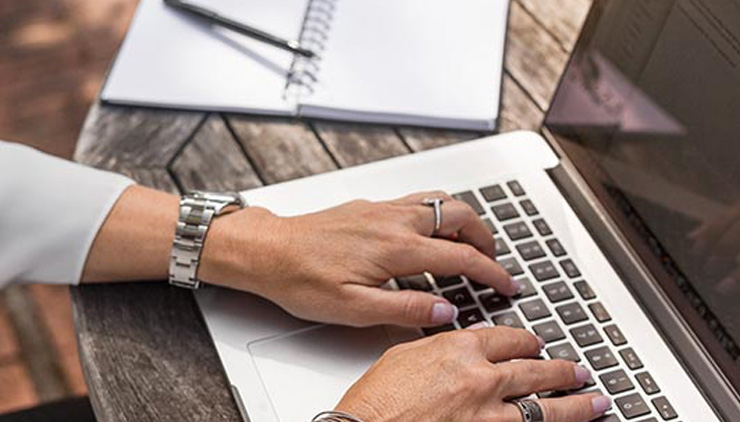 Person's hands on laptop typing outdoors