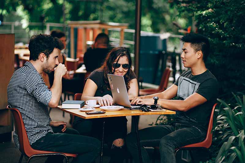 Students sitting down looking for a job on laptop while drinking coffee