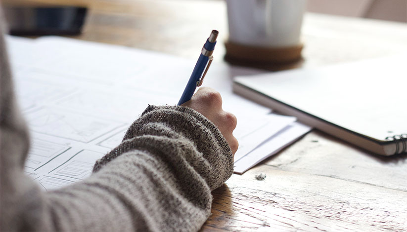 student writing on paper at a desk